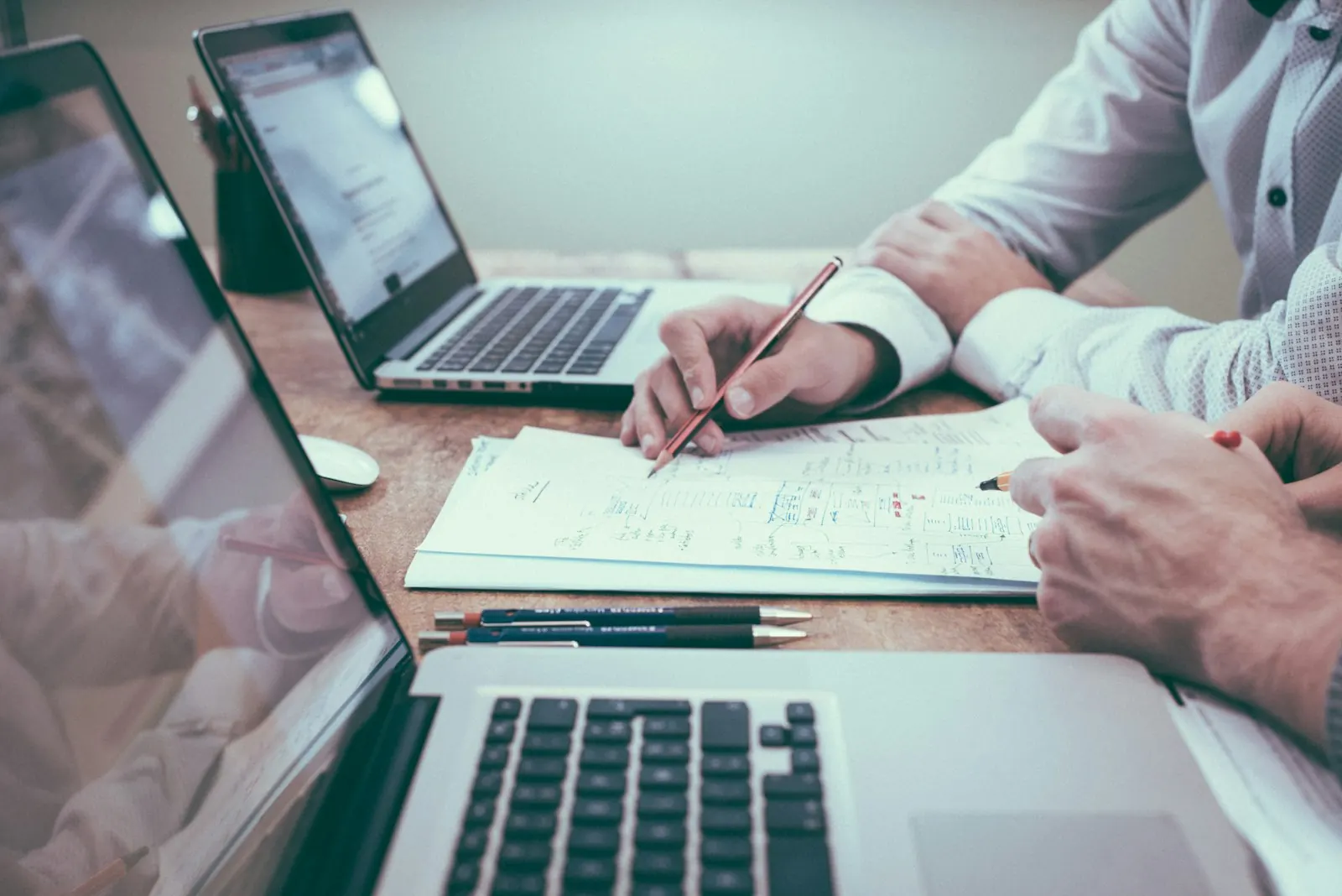 Two people marking up plan notes beside laptops